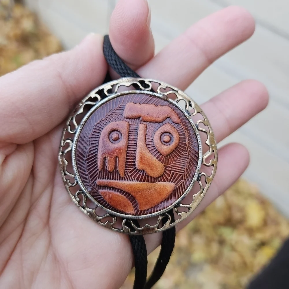 gold tone and brown leather abstract face bolo tie on black cord